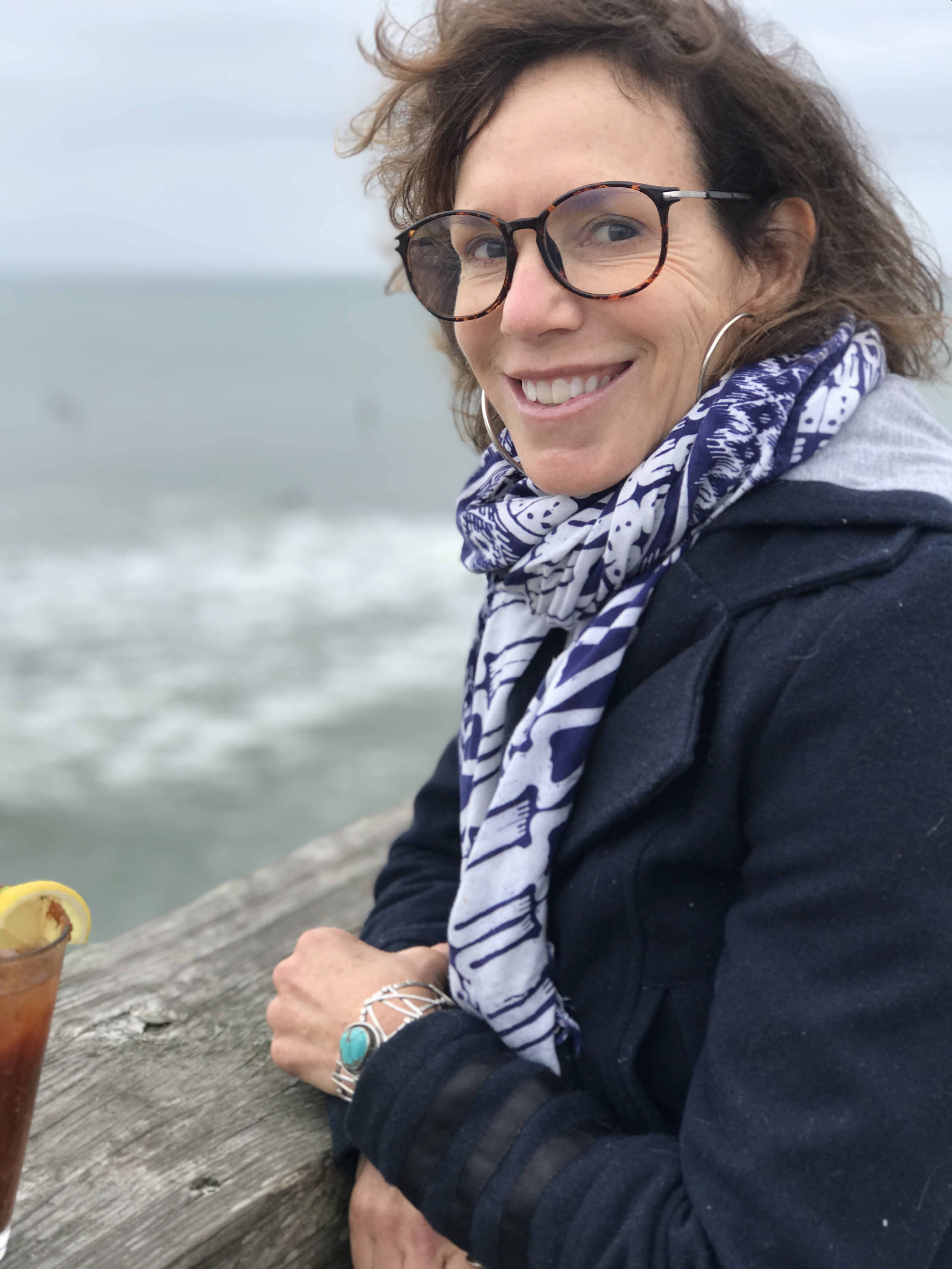 Terri Lefler of Lefler Design Studio smiling and standing on a pier over the Wrightsville Beach ocean SSM Creative Collective