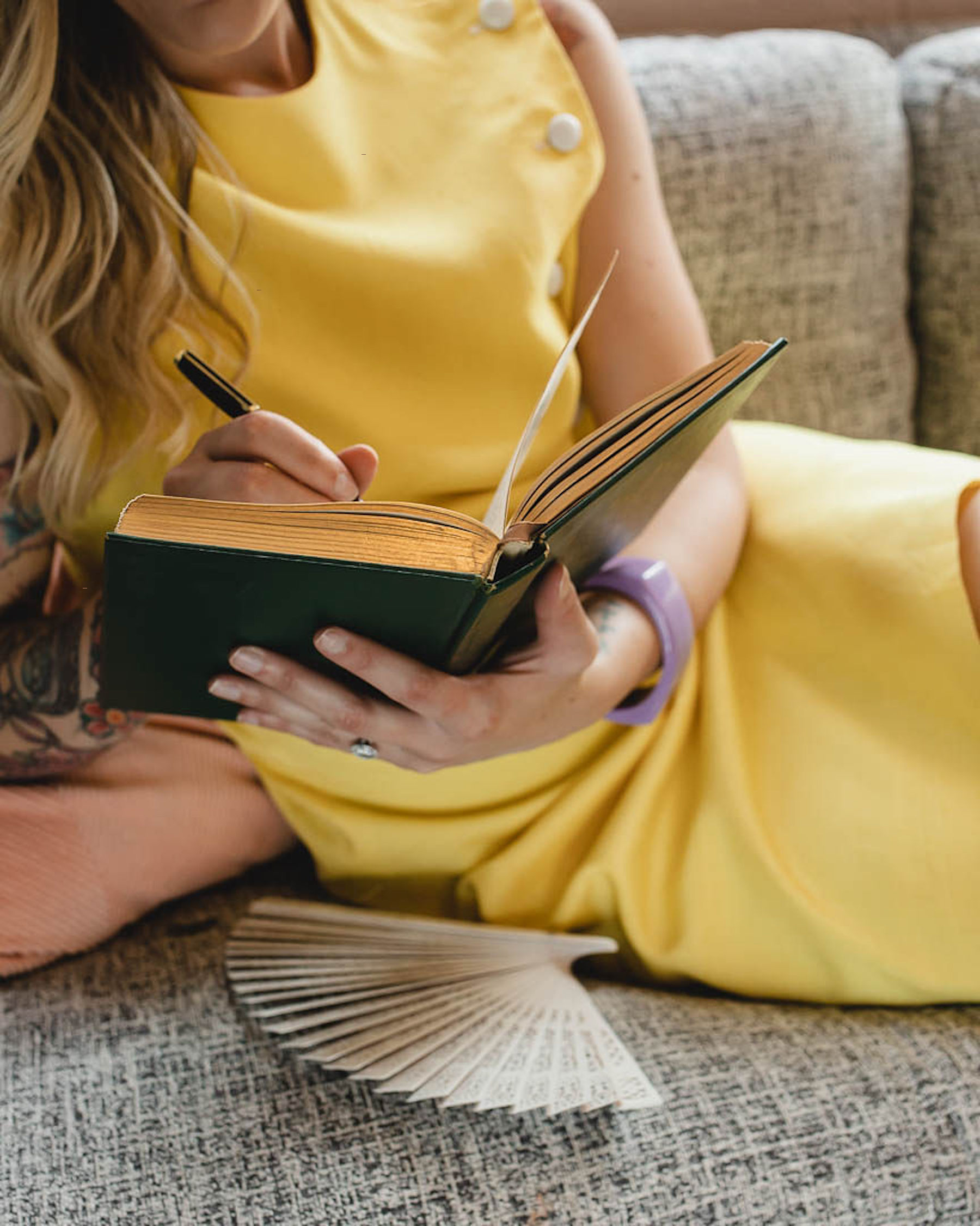 woman writing in journal on a sofa