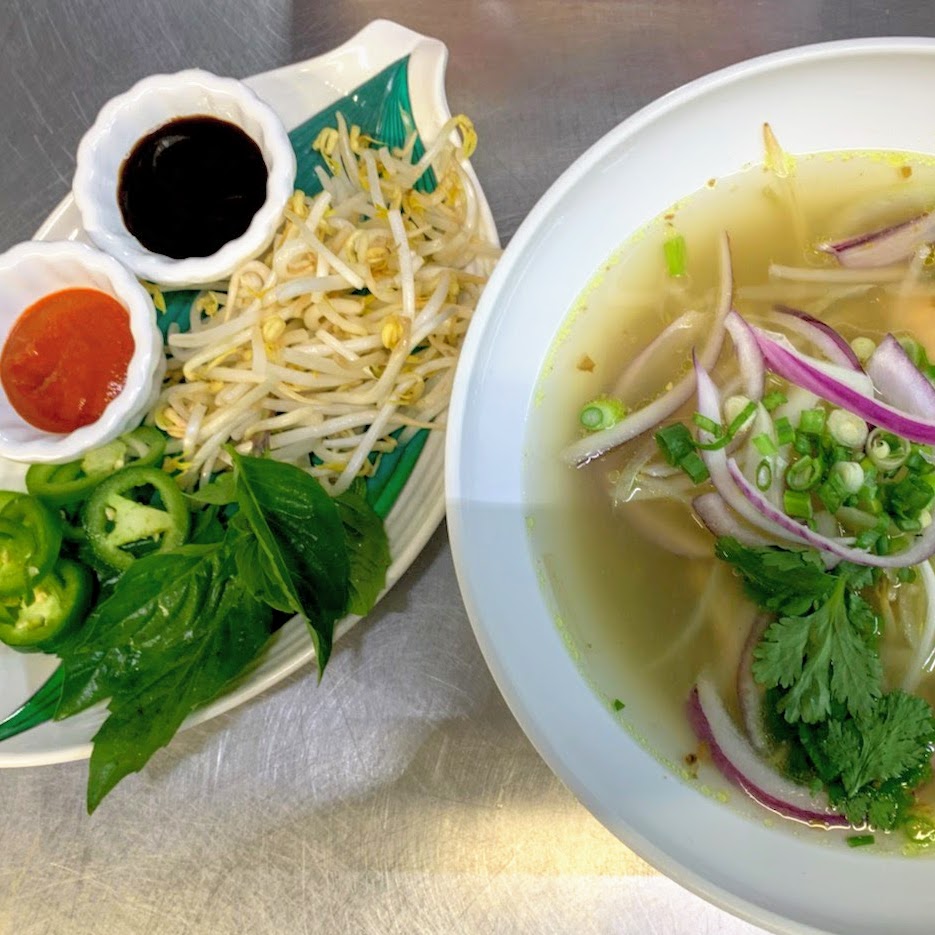 Bowl of pho, basil, jalapenos, sriracha and hoisin sauces on the side, vegan restaurants Indochine Wilmington, North Carolina