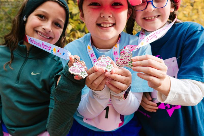 Girls from Girls on the Run presenting medals for participating in local athletics